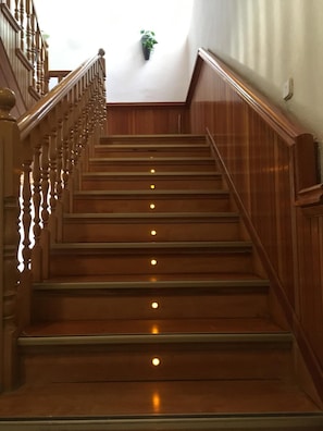 A wooden staircase with a handrail and a potted plant at the top. - Albergue Ciudad del Doncel (Siguenza)