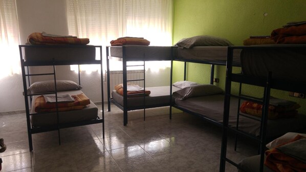 A dormitory room with bunk beds, a window with curtains, and a green wall. - Albergue Ciudad del Doncel (Siguenza)