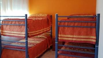 Ein Zimmer mit zwei Etagenbetten, einem fenster mit Vorhängen und einer orangefarbenen Wand.