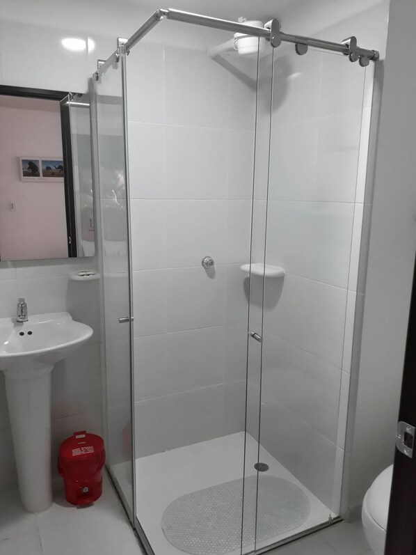 Une salle de bain moderne avec une douche à parois de verre, un lavabo blanc et des toilettes.