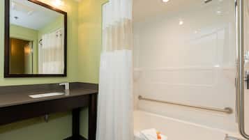 A bathroom with a sink, mirror, shower, and bathtub.