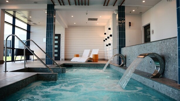 Un área de spa con hidromasaje, sillones de descanso y una escalera que conduce al nivel superior.