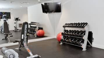 Une salle de sport équipée de matériel d’exercice, d’un téléviseur et d’un miroir.