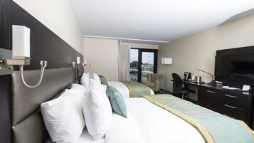A hotel room with a bed, a desk, a chair, a television, and a window with a view of the outside.