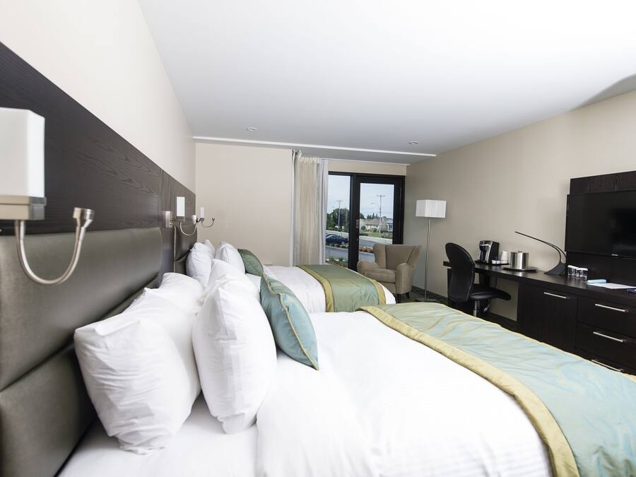A hotel room with a bed, a desk, a chair, a television, and a window with a view of the outside.