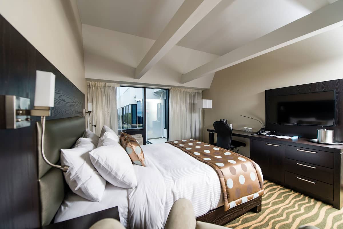 A hotel room with a bed, a desk, a television, and a view of the city.