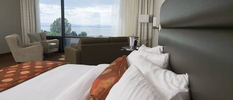 Habitación de hotel con una cama grande, un sofá, una silla y vistas al exterior.