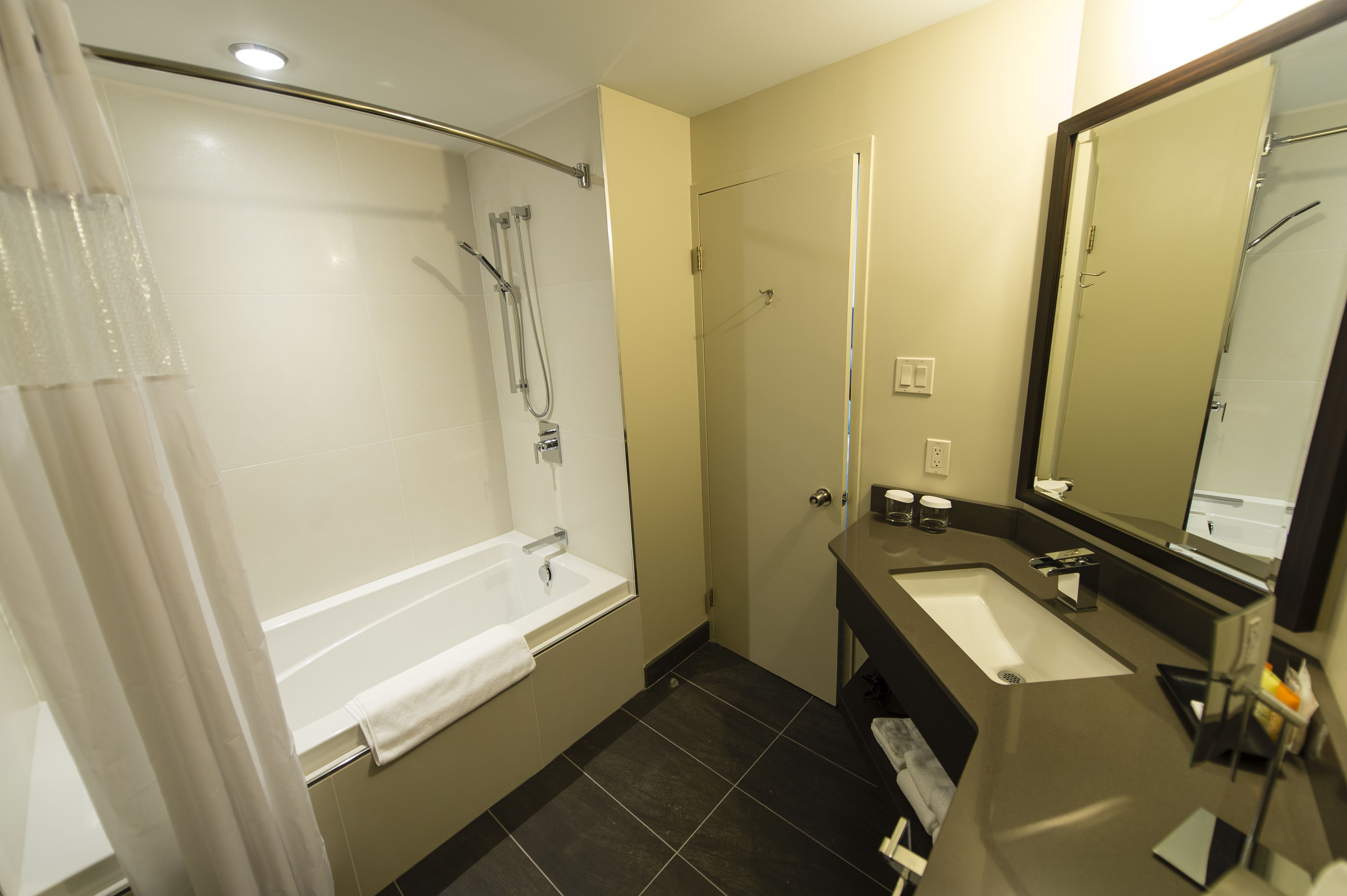 A modern bathroom with a bathtub, shower, and sink.