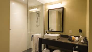 A modern bathroom with a glass-enclosed shower, a large mirror, and a black vanity with a white sink.