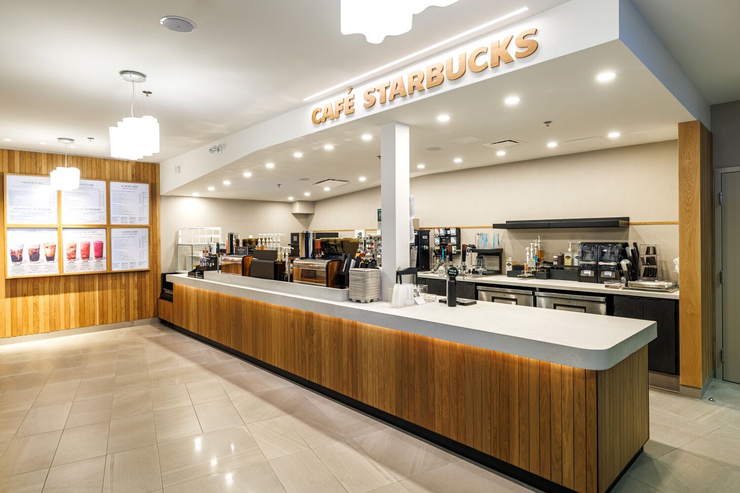 A modern Starbucks café with a wooden counter, espresso machines, and a menu board.