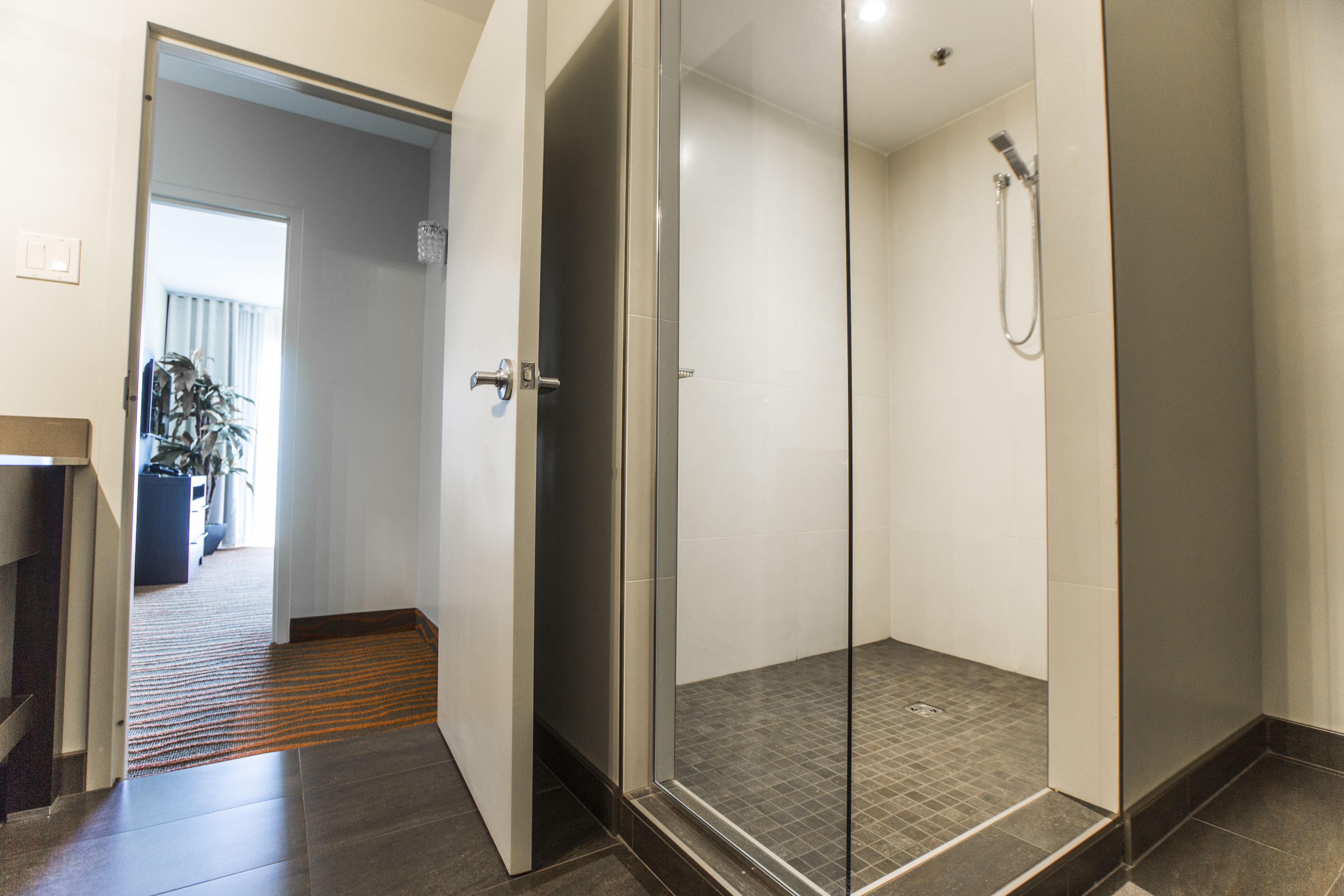 A modern bathroom with a glass shower enclosure, a visible showerhead, and a tiled floor.