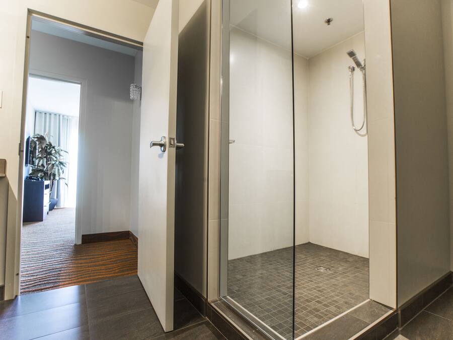 A modern bathroom with a glass shower enclosure, a visible showerhead, and a tiled floor.