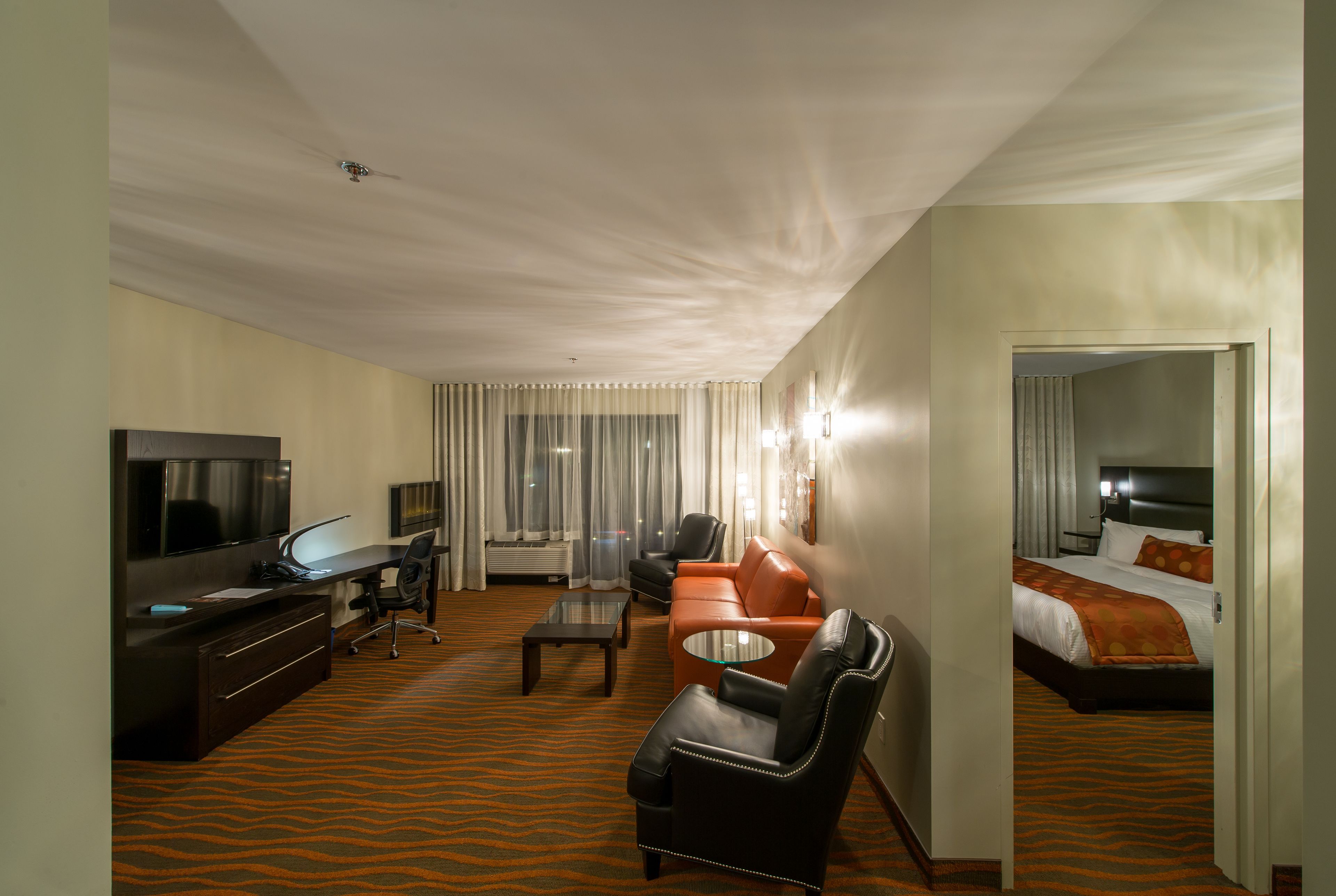 Een hotelkamer met een bed, een televisie, een bureau, een leren bank en een salontafel.