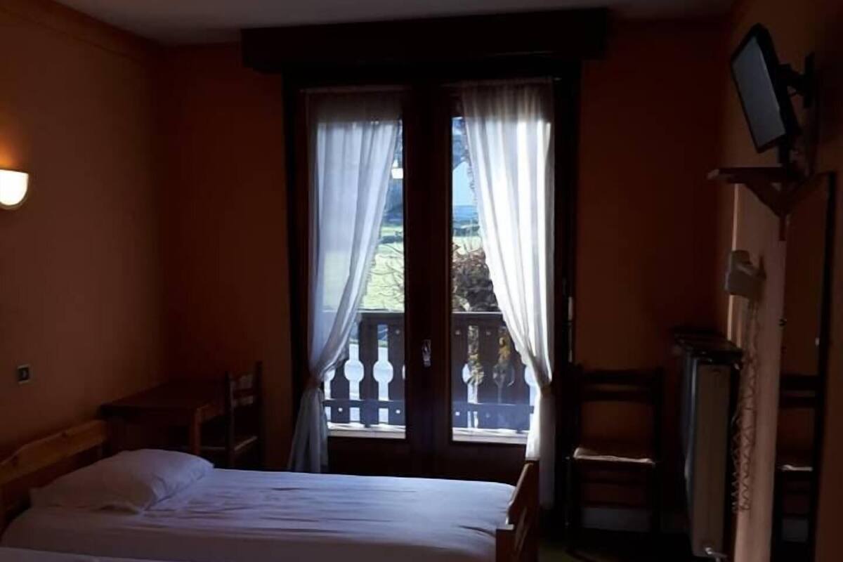 A hotel room with two beds, a balcony, a TV, and a desk.