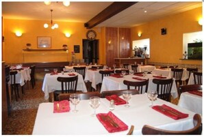 A restaurant with multiple tables, each set with white tablecloths and red napkins.