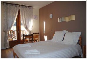Un dormitorio con cama, una silla, una mesa y una ventana con cortinas.