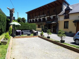 Un hotel con restaurante llamado "Hotel Restaurant" que ofrece mesas al aire libre, una terraza de madera y vistas a la montaña.