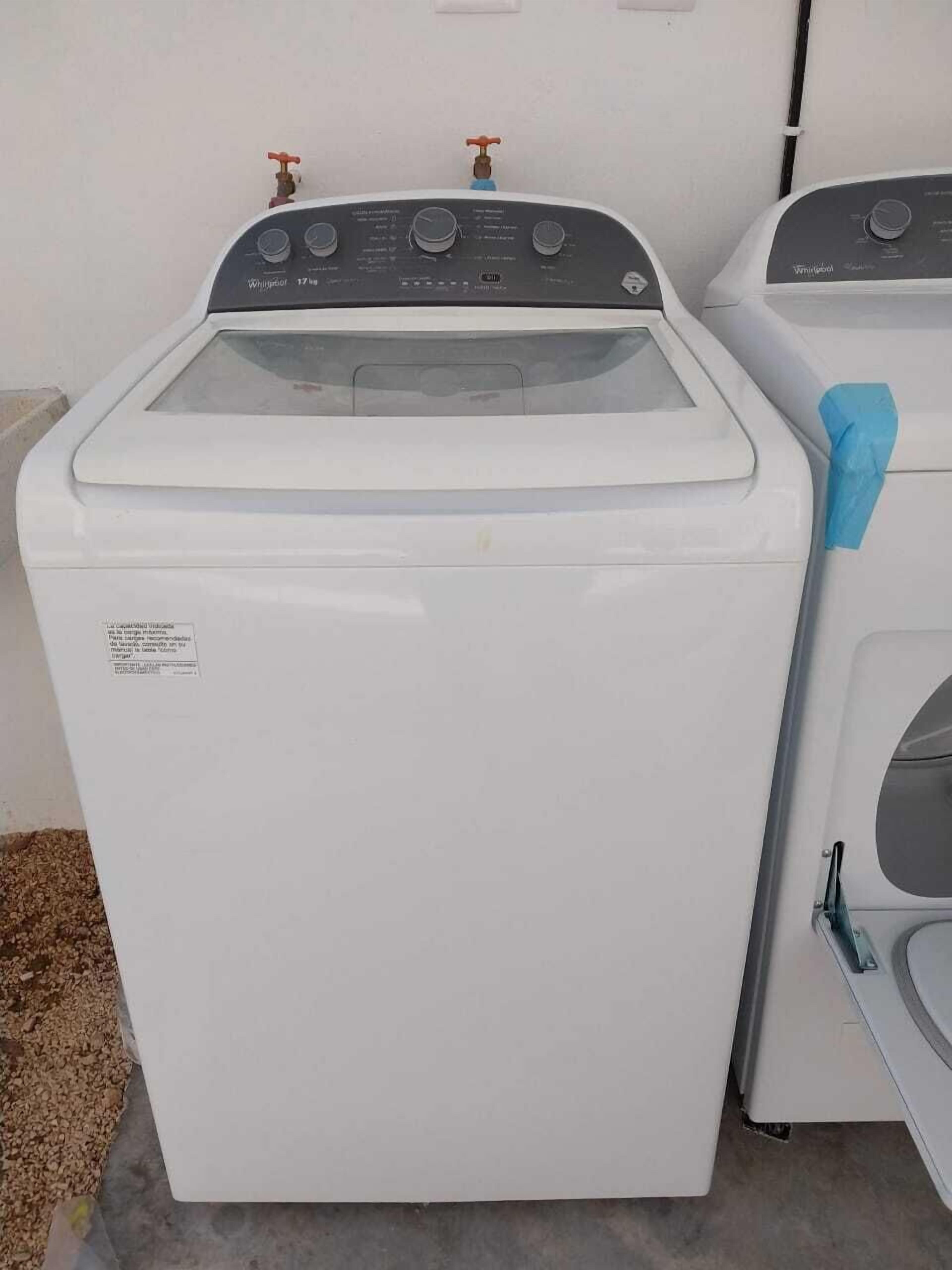 Eine Frontansicht einer weißen Waschmaschine mit Frontlader, einer Bedienblende und zwei Wasserhähnen obenauf.