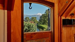 Une cabane en bois dotée d’une grande fenêtre donnant sur une chaîne de montagnes.