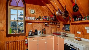 A cozy kitchen with wooden walls, a large window, and various kitchen appliances.