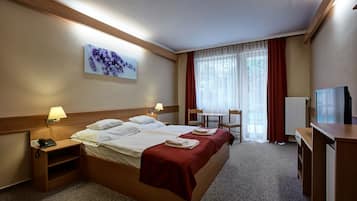 Ein Hotelzimmer mit einem Bett, Nachttischen, einem Schreibtisch, einem Sessel und einem Fernseher.