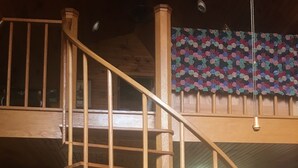 A wooden staircase leading to a loft area with a checkered floor and a kitchen in the background. - Merging Waters - Native Stone, couples cabin in the Ouachita Mts-with STARLINK (Smithville)
