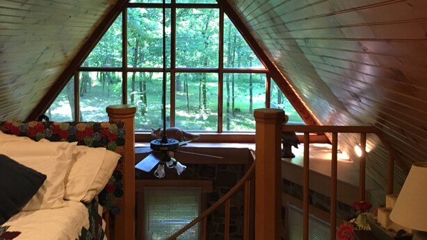 A cozy attic bedroom with a large window, a bed, and a desk area. - Merging Waters - Native Stone, couples cabin in the Ouachita Mts-with STARLINK (Smithville)