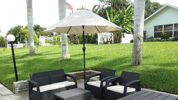 Eine Terrasse im Freien mit Korbmöbeln, einem Tisch und einem großen Sonnenschirm.