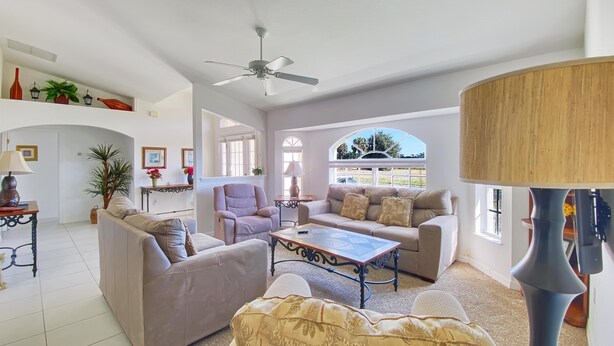 A spacious living room with a ceiling fan, a sofa set, a coffee table, and a lamp. - Tropical Retreat, full refund*, heated pool, dog ok (Rotonda West)
