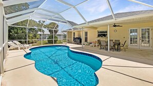 A covered swimming pool with lounge chairs and a patio area with outdoor furniture. - Tropical Retreat, full refund*, heated pool, dog ok (Rotonda West)