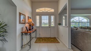 A hallway with a white door, a lamp on a table, and a view to a balcony. - Tropical Retreat, full refund*, heated pool, dog ok (Rotonda West)