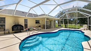 A covered swimming pool with a patio area, a grill, and a seating arrangement. - Tropical Retreat, full refund*, heated pool, dog ok (Rotonda West)