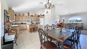 A spacious kitchen with a central island, a dining area with a large table and chairs, and a view of the outdoors through a window. - Tropical Retreat, full refund*, heated pool, dog ok (Rotonda West)
