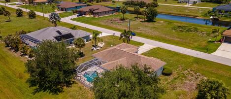 An aerial view of a residential area with houses, a swimming pool, and a small lake.