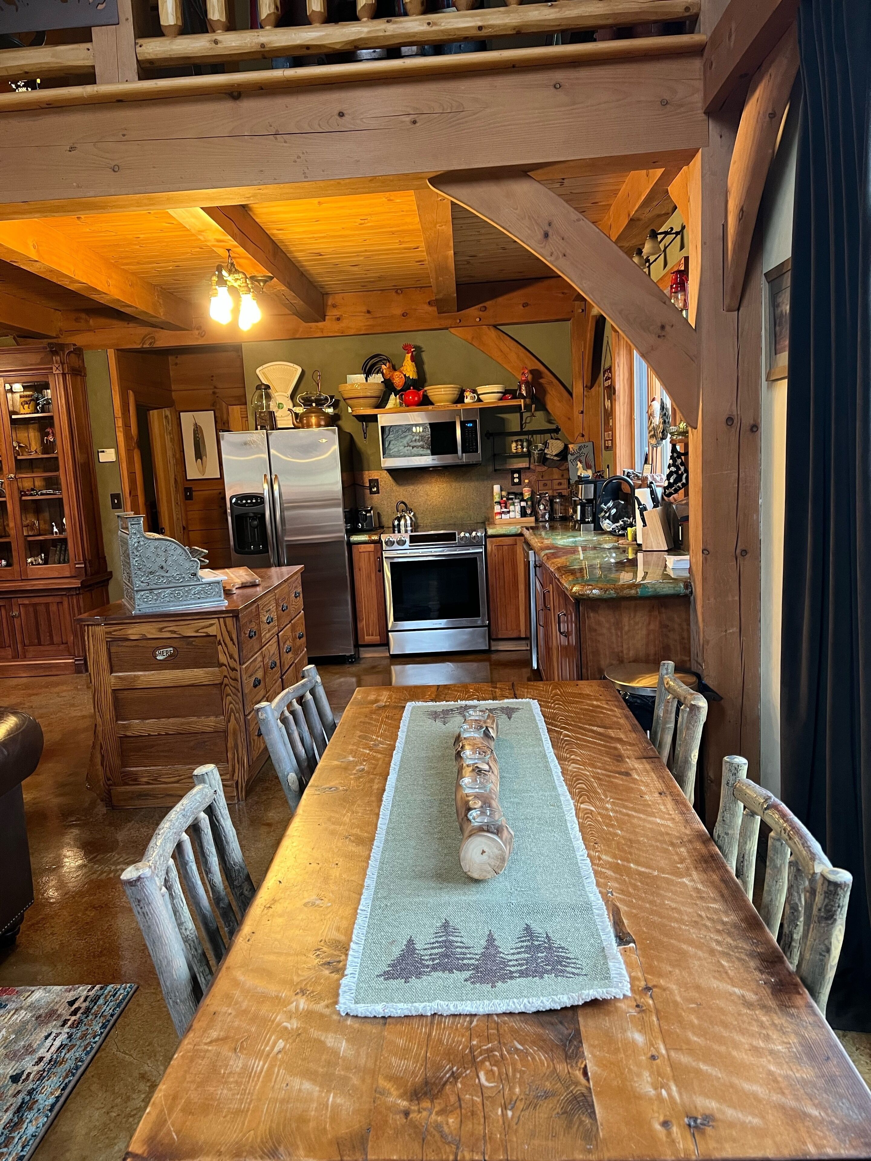 A spacious kitchen with wooden beams, a dining table with chairs, and a central island with a sink and stove.