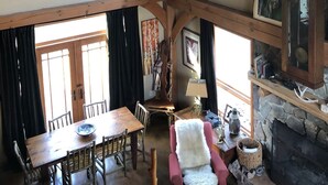 A rustic interior with a wooden ceiling, stone walls, a dining area with a table and chairs, and a fireplace. - WILLOW RUN LODGE  an Authentic Timber Frame Cabin on private 35 acres with river (Blakeslee)