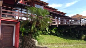 A two-story building with a red facade, a wooden balcony, and a stone wall. - PARADISE! HOUSE IN ANGRA DOS REIS + BOAT FOR TOURS IN ILHA GRANDE (Angra dos Reis)