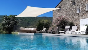 A pool with clear blue water, surrounded by lounge chairs and a white canopy.