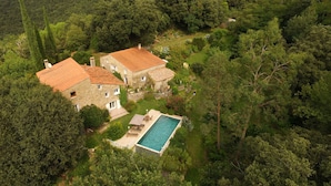 A stone house with a swimming pool surrounded by lush greenery and hills.