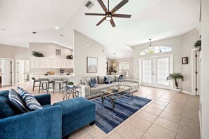 A spacious living room with a sofa, coffee table, and a dining area with chairs.