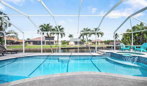 A swimming pool with a view of a residential area, including houses and palm trees.