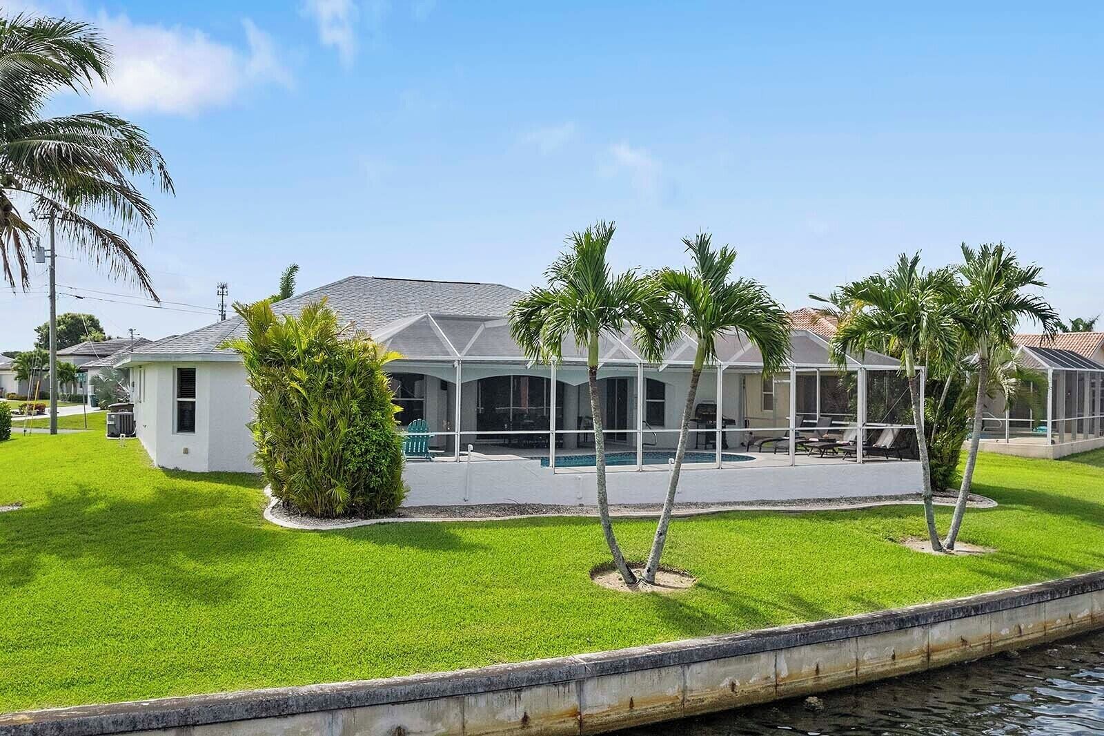 A residential property with a covered patio, a swimming pool, and a well-maintained lawn.