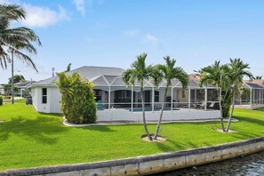 A residential property with a covered patio, a swimming pool, and a well-maintained lawn.