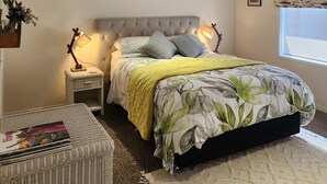 A bedroom with a bed, bedside lamps, a bedside table, a window with a floral curtain, and a small side table with a magazine. -  Farm stay-Tranquil & quiet, relaxation country style (Sentry Hill)