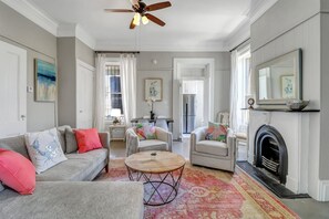 A living room with a fireplace, a ceiling fan, and a dining area.