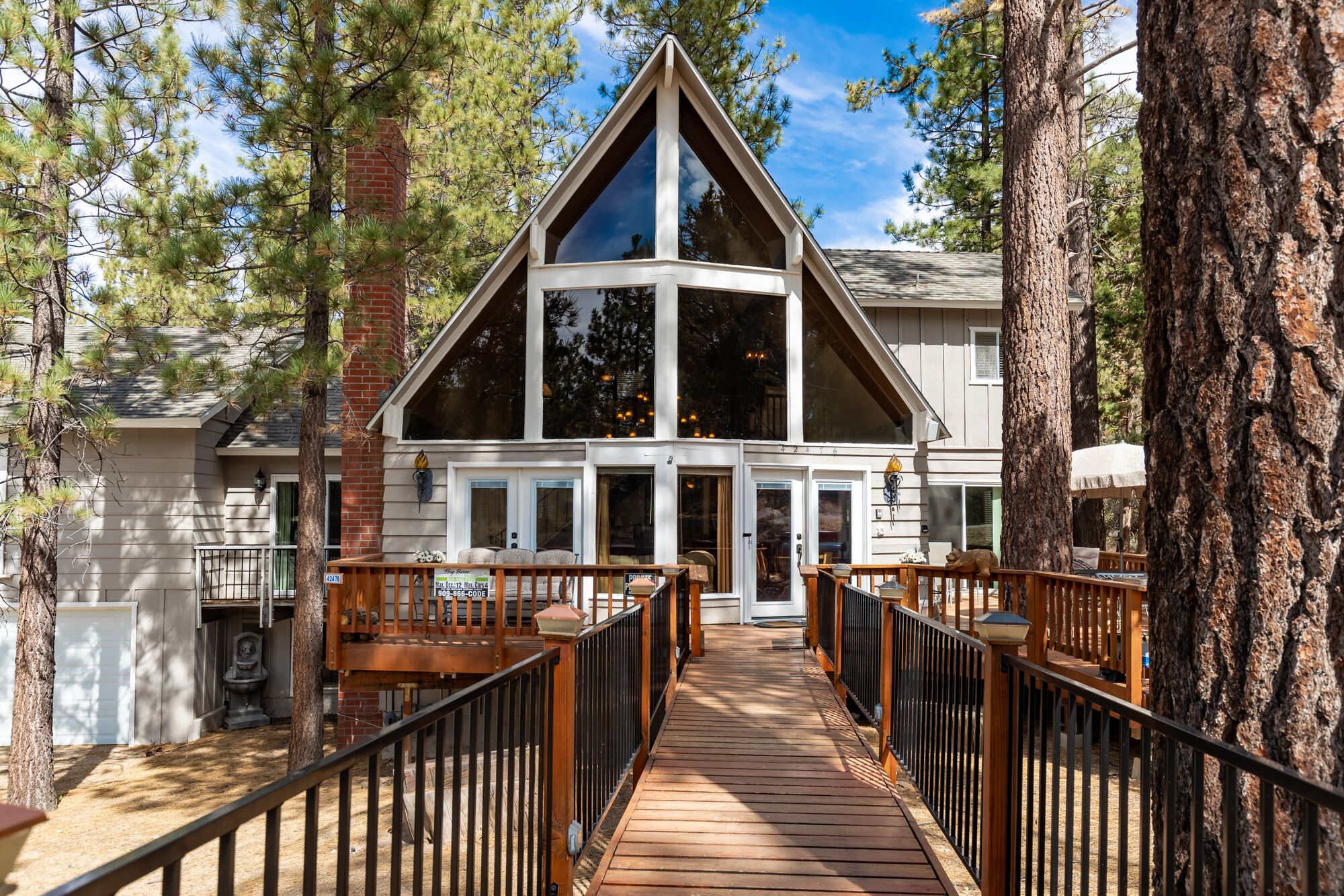 Welcoming cabin entry surrounded by towering pine trees, offering fresh mountain air and a peaceful forest setting—the perfect first impression for your Big Bear Lake getaway.