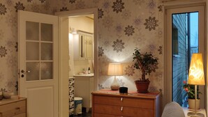 A cozy living room with a wooden ceiling, a sofa, a coffee table, a dresser, and a lamp. - Väike-Kuke Dream Apartment (Pärnu)