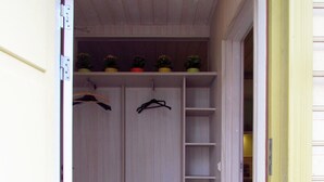 A walk-in closet with hanging space and shelves, a tiled floor, and a door leading to another room. - Väike-Kuke Dream Apartment (Pärnu)