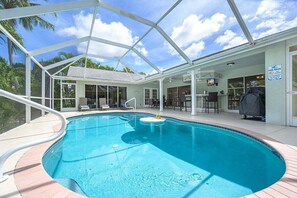 A pool area with a covered deck, lounge chairs, and a pool rule sign. - Hideaway 4 bedroom with den, 2 bathroom located on (Cape Coral)