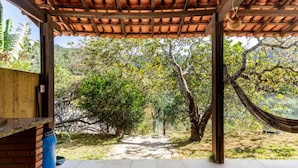 A covered outdoor area with a tiled floor, a brick wall, and a hammock. - Wonderful farmhouse in Bragança, a refuge close to São Paulo. (Chácaras Fernão Dias)